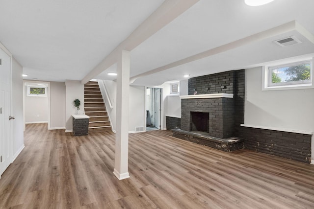 2237 Holloway Ave E, North Saint Paul, MN 55109 - unfurnished living room with wood finished floors, a fireplace, stairs, baseboards, and healthy amount of natural light