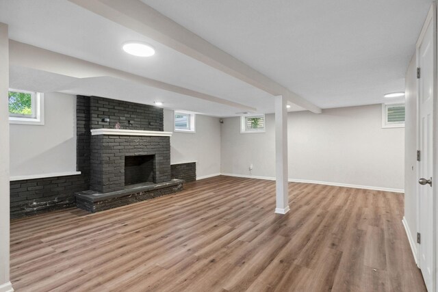 2237 Holloway Ave E, North Saint Paul, MN 55109 - unfurnished living room featuring a brick fireplace, wood finished floors, plenty of natural light, and baseboards