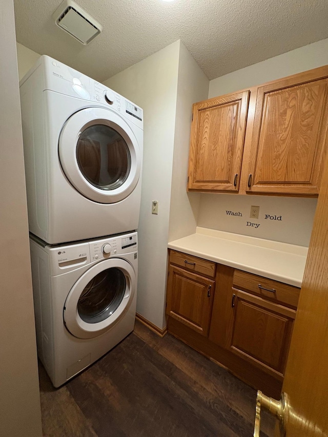 40 Broadway, Plainview, MN 55964 - laundry area featuring stacked washing machine and dryer, cabinet space, dark wood-style floors, and a textured ceiling