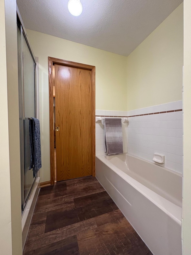 40 Broadway, Plainview, MN 55964 - full bathroom featuring wood finished floors, a bath, a stall shower, and a textured ceiling