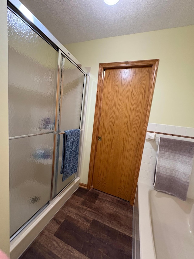 40 Broadway, Plainview, MN 55964 - bathroom featuring wood finished floors, a stall shower, a bath, a textured ceiling, and wainscoting