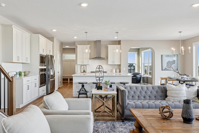 5107 Allen Dr, Woodbury, MN 55129 - living room with plenty of natural light, arched walkways, recessed lighting, light wood-style flooring, and a chandelier