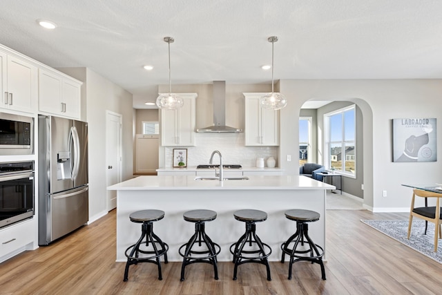 5107 Allen Dr, Woodbury, MN 55129 - kitchen featuring stainless steel appliances, wall chimney exhaust hood, a breakfast bar, baseboards, and recessed lighting