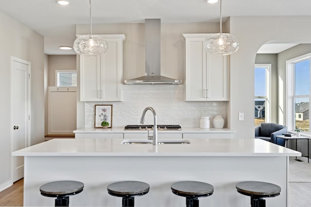 5107 Allen Dr, Woodbury, MN 55129 - kitchen featuring wall chimney range hood, a breakfast bar, backsplash, white cabinets, and recessed lighting