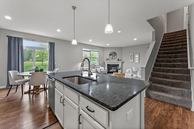 6317 153rd St, Savage, MN 55378 - kitchen featuring a sink, a glass covered fireplace, dark wood-style floors, an island with sink, and white cabinetry