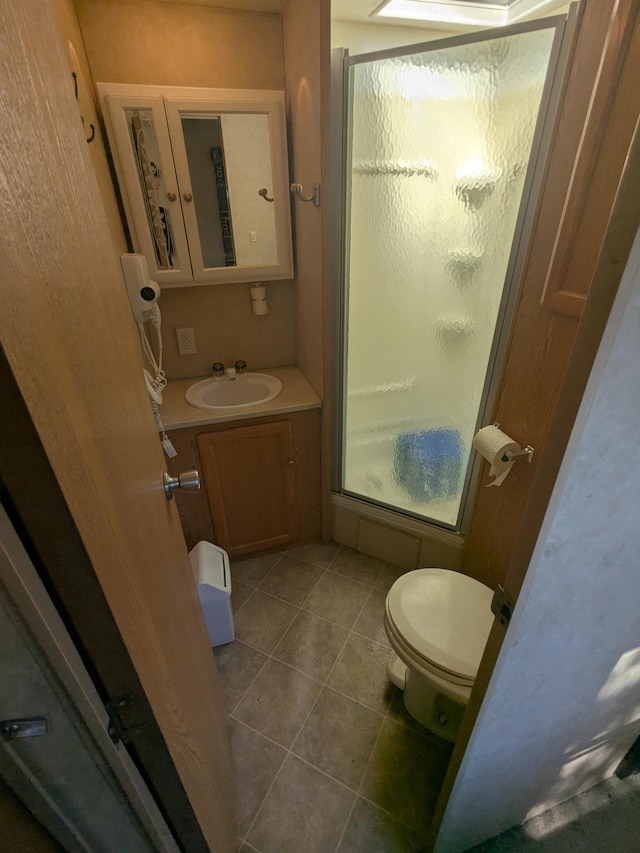bathroom with a stall shower, vanity, tile patterned floors, and toilet