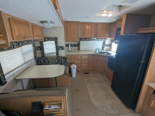 kitchen with freestanding refrigerator, light countertops, a sink, and backsplash
