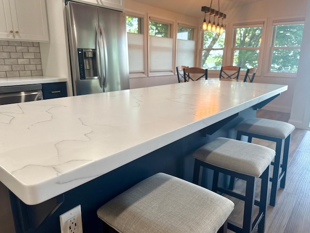 30558 376th Ave, Nordland Twp, MN 56431 - kitchen with stainless steel appliances, wood finished floors, white cabinetry, tasteful backsplash, and hanging light fixtures