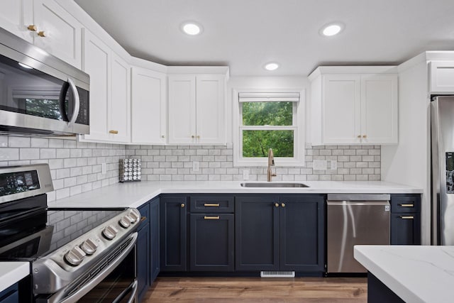 30558 376th Ave, Nordland Twp, MN 56431 - kitchen featuring stainless steel appliances, white cabinetry, blue cabinets, backsplash, and recessed lighting