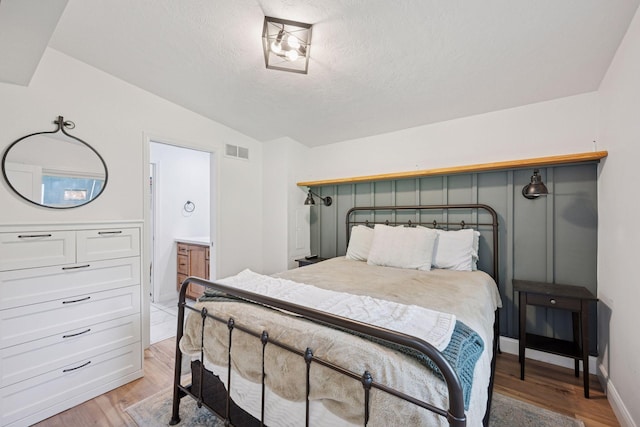 30558 376th Ave, Nordland Twp, MN 56431 - bedroom featuring light wood finished floors, a textured ceiling, vaulted ceiling, and ensuite bath