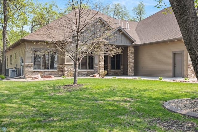 106 Beaton Dr, West Fargo, ND 58078 - view of front of house with stone siding, a front yard, and central AC unit