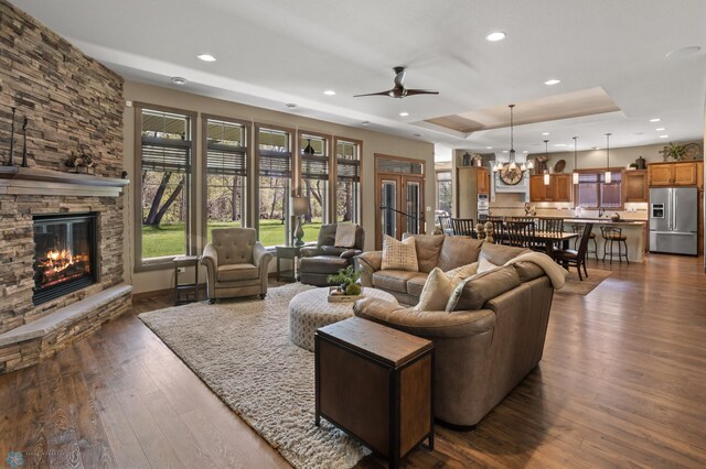 106 Beaton Dr, West Fargo, ND 58078 - living area with dark wood-style floors, a fireplace, recessed lighting, a tray ceiling, and ceiling fan