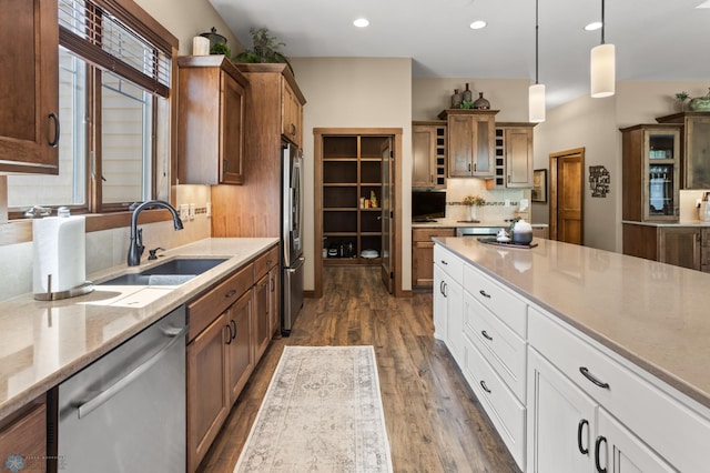 106 Beaton Dr, West Fargo, ND 58078 - kitchen featuring stainless steel appliances, a sink, dark wood-style floors, hanging light fixtures, and decorative backsplash