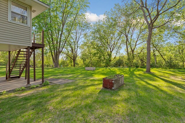 16 Crestview Bay, Faribault, MN 55021 - view of green lawn featuring stairs, a deck, and view of wooded area
