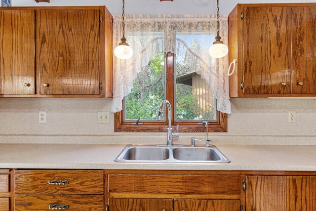 16 Crestview Bay, Faribault, MN 55021 - kitchen with a sink, light countertops, brown cabinetry, and hanging light fixtures