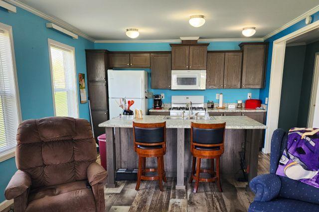 305 4th Ave SW, Milltown, WI 54858 - kitchen featuring white appliances, open floor plan, dark brown cabinetry, a kitchen island with sink, and dark wood-style floors