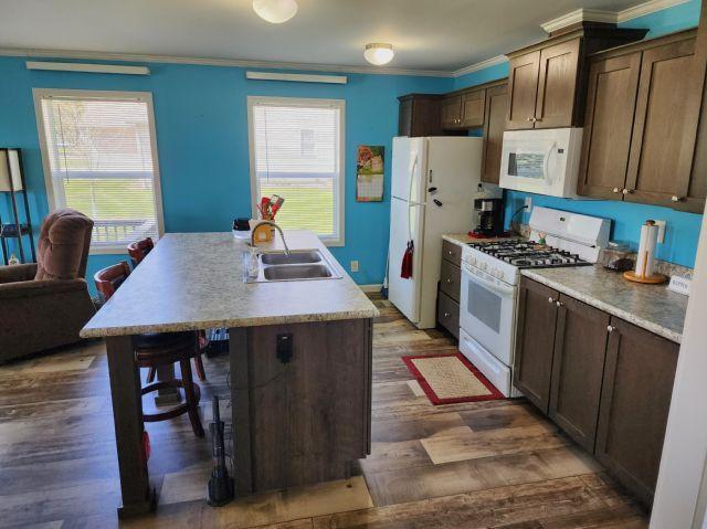305 4th Ave SW, Milltown, WI 54858 - kitchen with white appliances, a sink, a center island with sink, crown molding, and dark wood-style floors