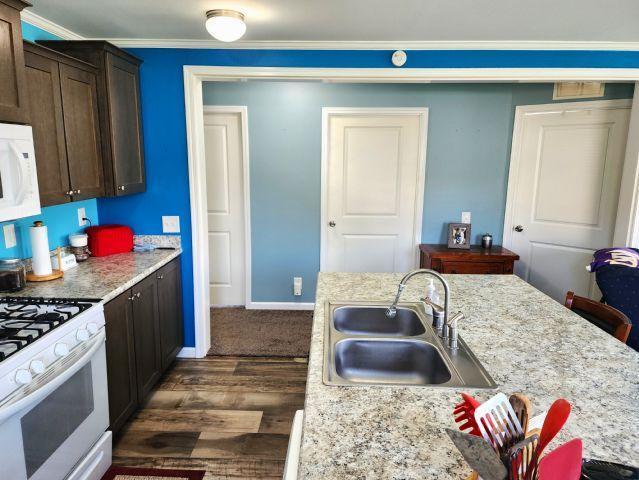 305 4th Ave SW, Milltown, WI 54858 - kitchen featuring white appliances, a sink, dark wood-style floors, dark brown cabinetry, and baseboards