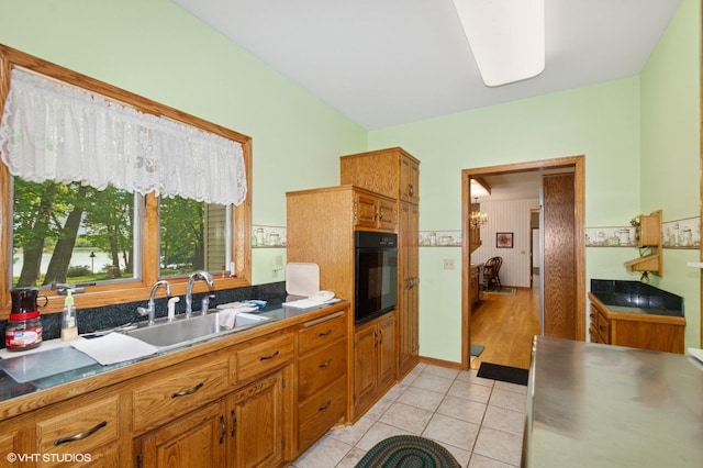 28075 Zuni St NW, Isanti, MN 55040 - kitchen featuring black oven, brown cabinets, light tile patterned flooring, and a sink