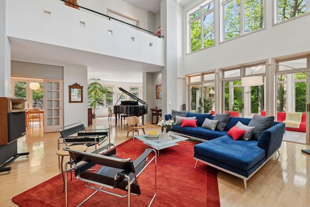 living area with plenty of natural light, wood finished floors, and a towering ceiling