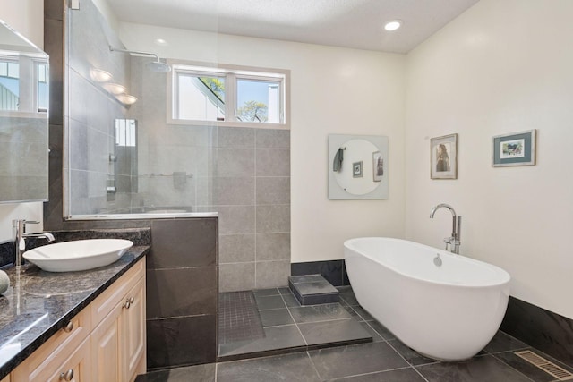 bathroom featuring walk in shower, double vanity, a freestanding tub, and tile patterned flooring