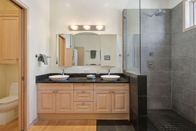 full bathroom featuring walk in shower, toilet, double vanity, and wood finished floors