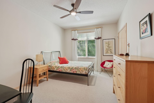 bedroom with a textured ceiling, light carpet, and ceiling fan