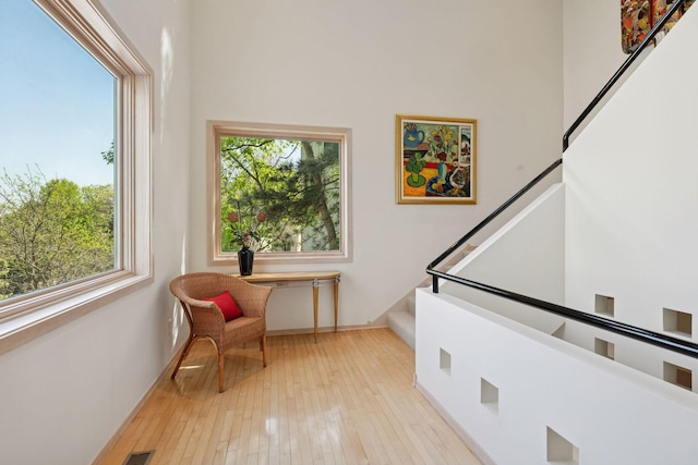 sitting room featuring plenty of natural light, stairs, baseboards, and hardwood / wood-style flooring