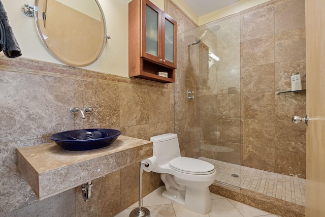 bathroom featuring a tile shower, toilet, a sink, and tile walls