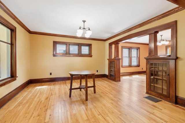 unfurnished dining area featuring a chandelier, light wood finished floors, baseboards, and ornamental molding