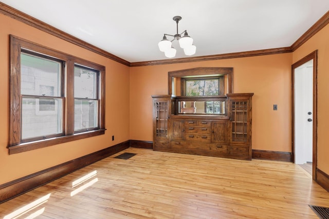 unfurnished room with baseboards, crown molding, a chandelier, and light wood-style floors