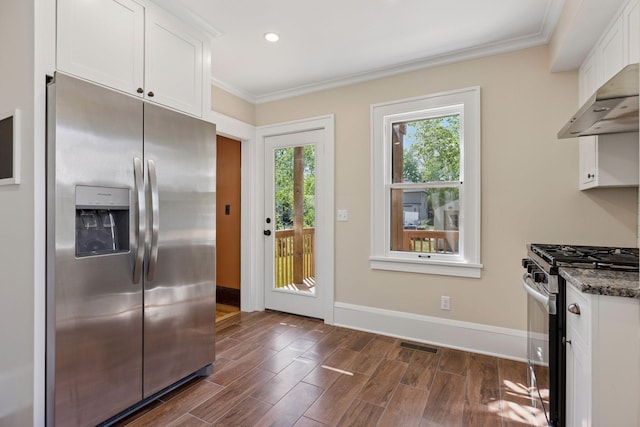 kitchen with appliances with stainless steel finishes, white cabinets, dark wood-style flooring, crown molding, and dark stone counters