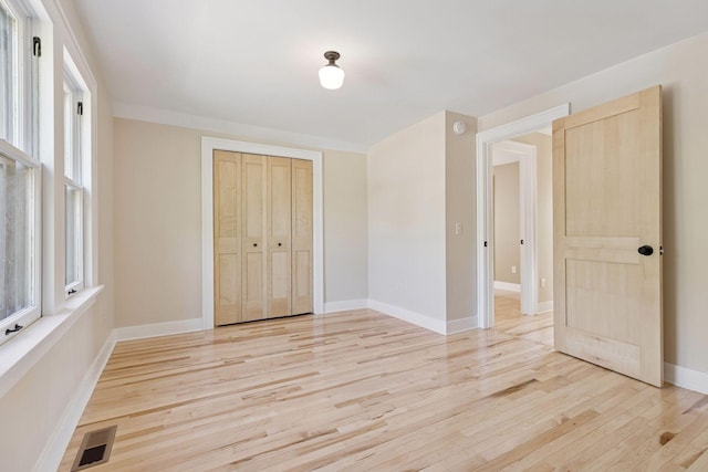 unfurnished bedroom with light wood finished floors, a closet, and baseboards