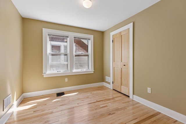 unfurnished bedroom featuring light wood-style floors, baseboards, and a closet