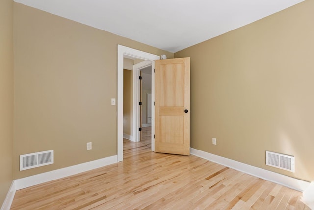 spare room with baseboards and light wood finished floors