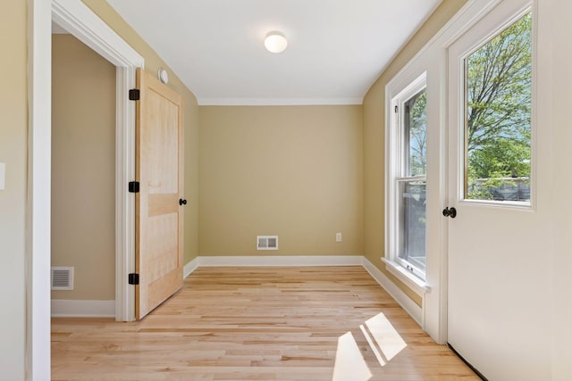 spare room featuring plenty of natural light, light wood-style flooring, and baseboards
