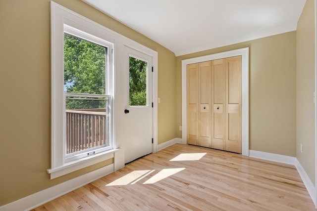 unfurnished bedroom featuring light wood-style flooring, baseboards, and a closet