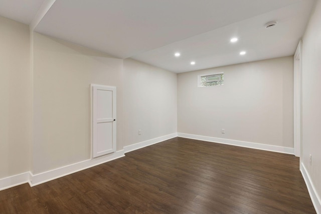 below grade area with dark wood finished floors, recessed lighting, and baseboards