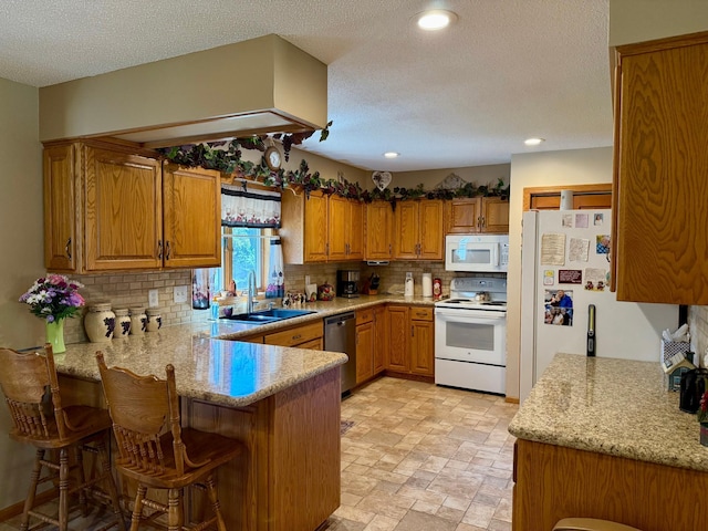 kitchen with white appliances, a sink, a peninsula, backsplash, and brown cabinets