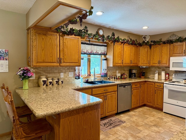 kitchen with white appliances, a textured ceiling, a sink, a peninsula, and tasteful backsplash