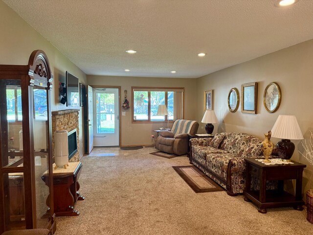living room featuring carpet flooring, recessed lighting, a stone fireplace, and a textured ceiling