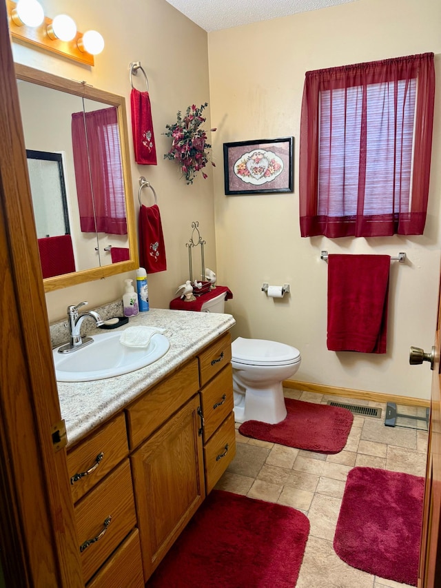 bathroom featuring toilet, vanity, and baseboards