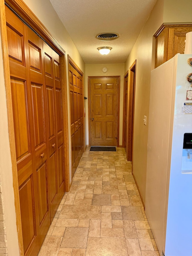 hall with stone tile floors and a textured ceiling