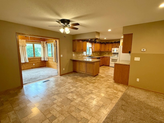 2705 6th St SW, Willmar, MN 56201 - kitchen with white appliances, a peninsula, brown cabinetry, ceiling fan, and stone tile floors