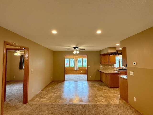2705 6th St SW, Willmar, MN 56201 - kitchen featuring ceiling fan, brown cabinetry, light countertops, recessed lighting, and light colored carpet