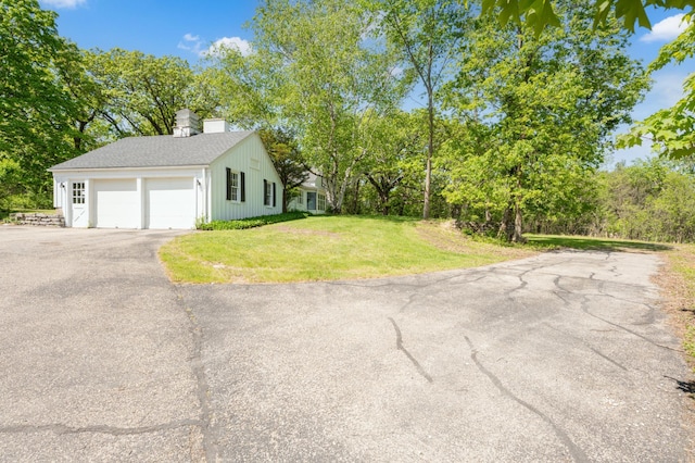 1429 20th St SW, Rochester, MN 55902 - view of home's exterior with an attached garage, asphalt driveway, a lawn, a chimney, and view of wooded area