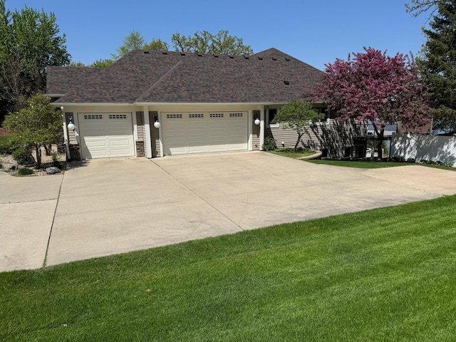 view of front of house with a garage, concrete driveway, a front yard, and a shingled roof