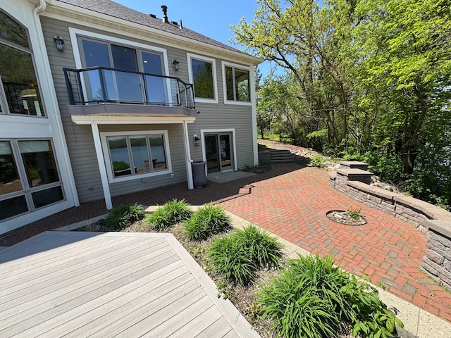 back of property featuring a balcony, a patio, and a wooden deck