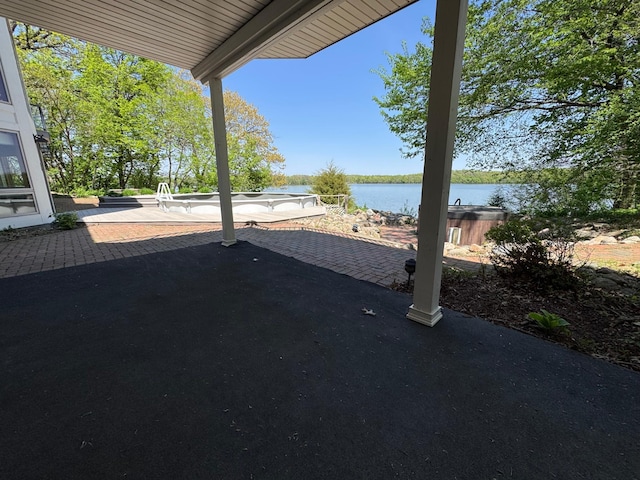 view of patio featuring a water view and a hot tub