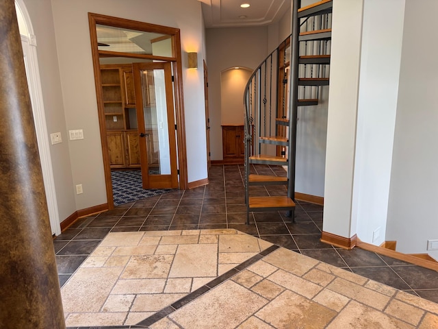 entrance foyer featuring baseboards, arched walkways, stairs, and stone tile floors